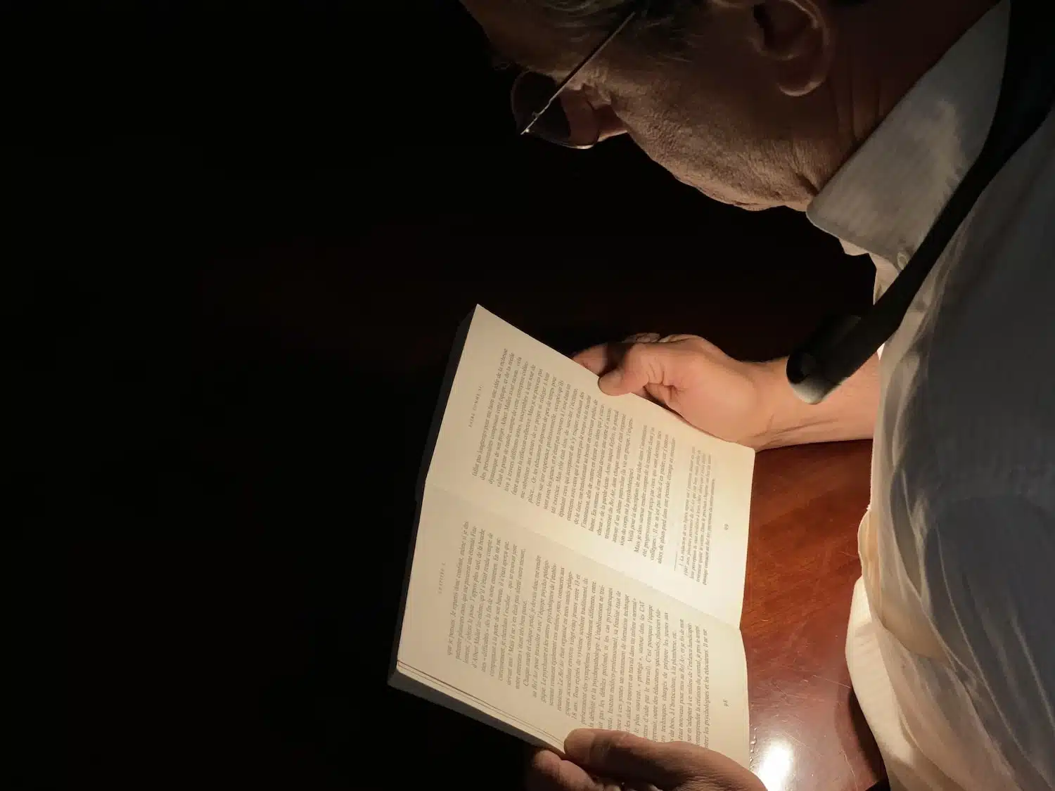 Lampe tour de cou AINA, portée, éclairant un livre pour DMLA