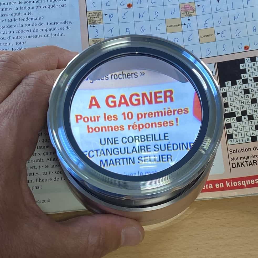 Loupe dôme éclairante rechargeable posée sur un magazine pour faciliter la lecture en cas de DMLA