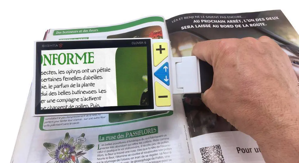 La loupe électronique CLOVER 5 tenue à la main et grossissant une partie du texte d’un magazine.
