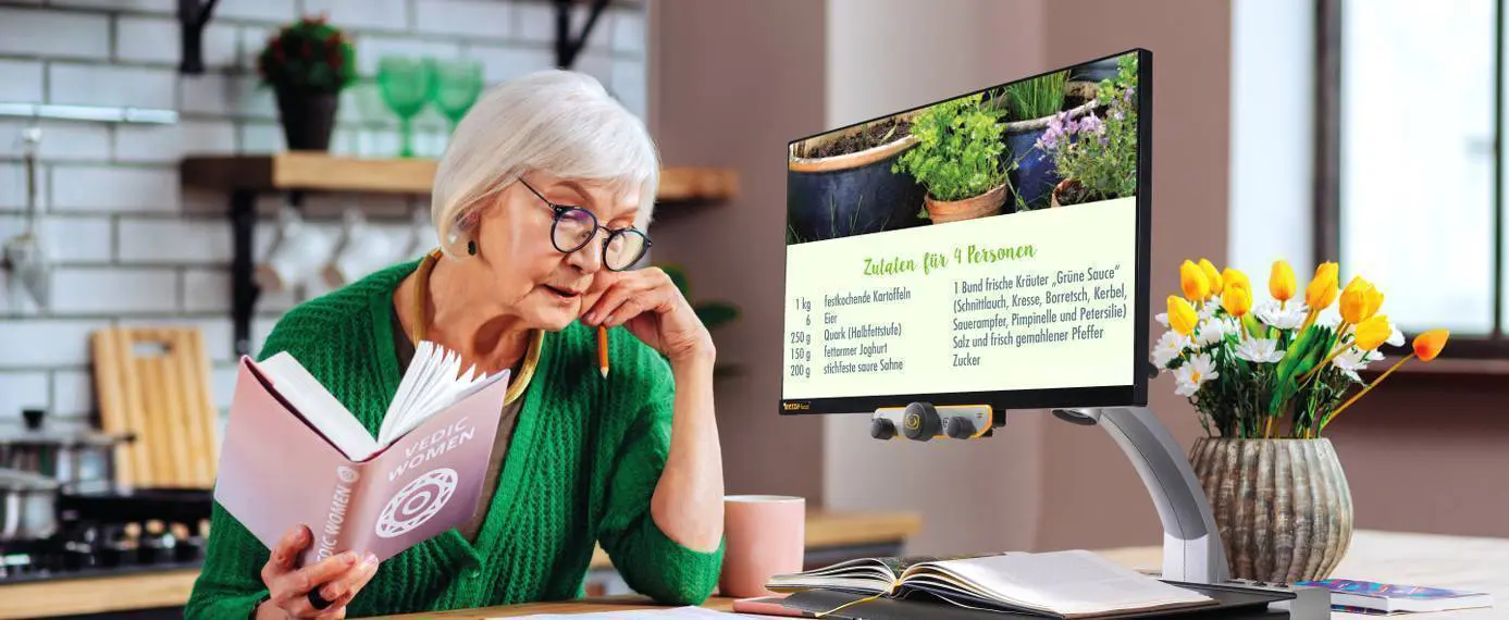 Une personne âgée atteinte de basse vision lit grâce au téléagrandisseur MEZZO